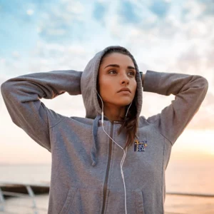 modella durante un allenamento sul mare che indossa una felpa zip e cappuccio personalizzata sul lato cuore