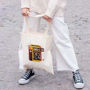 modella in piedi che tiene per i manici una shopper tote bag di cotone colore naturale